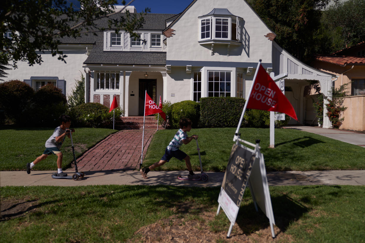 Children ride scooters past and 'open house' flags displayed outside a single family home on September 22, 2022 in Los Angeles, California. The U.S. housing market is seeing a slow down in home sales due to the Federal Reserve raising mortgage interest rates to help fight inflation. (Credit: Allison Dinner, Getty Images)