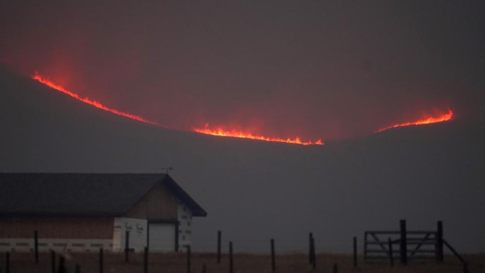 Riesige Flammen steigen über einem Bergkamm auf.