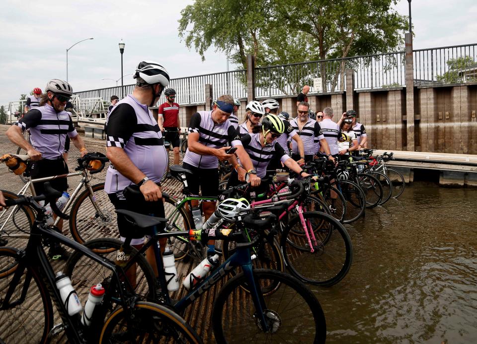 Members of the RAGBRAI route inspection team dip their tires in the Mississippi River in Davenport as the ride concludes Saturday.