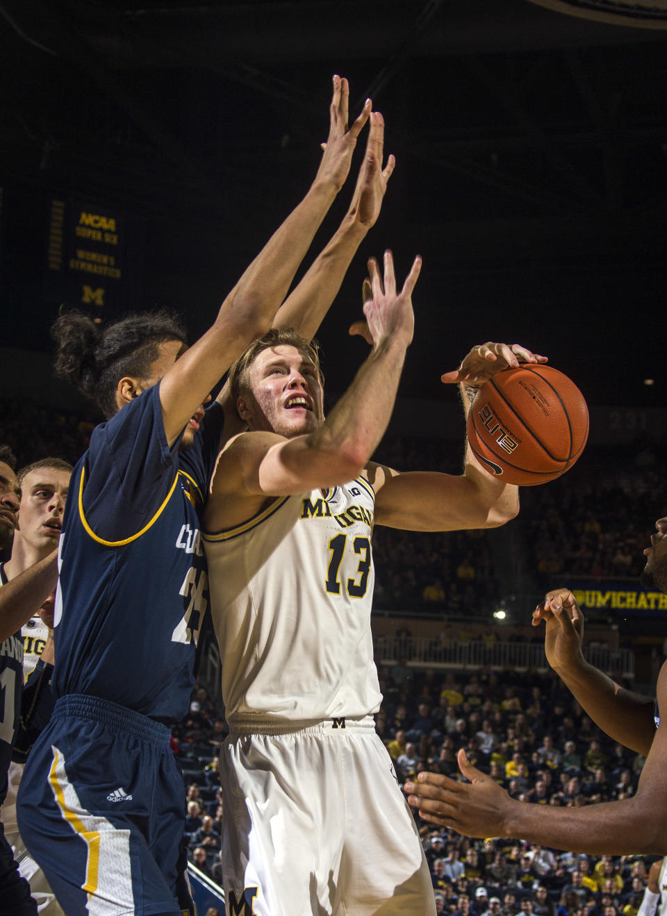 Chattanooga center Justin Brown, left, defends against Michigan forward Ignas Brazdeikis (13) under the basket in the second half of an NCAA college basketball game at Crisler Center in Ann Arbor, Mich., Friday, Nov. 23, 2018. (AP Photo/Tony Ding)