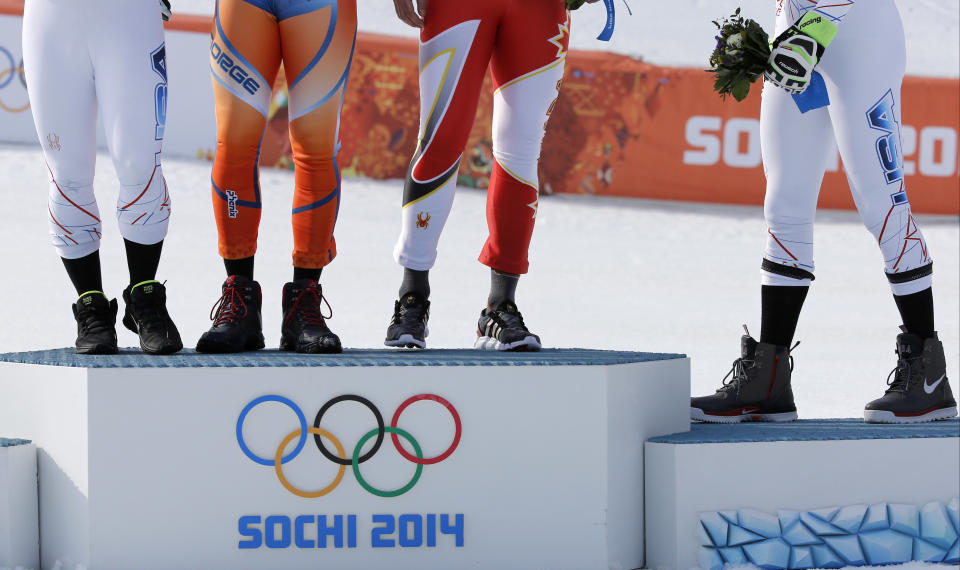 Men's super-G medalists, from left United States' Andrew Weibrecht (silver), Norway's Kjetil Jansrud (gold), Canada's Jan Hudec (bronze) and United States' Bode Miller (bronze) stand on the podium for a flower ceremony at the Sochi 2014 Winter Olympics, Sunday, Feb. 16, 2014, in Krasnaya Polyana, Russia.(AP Photo/Christophe Ena)