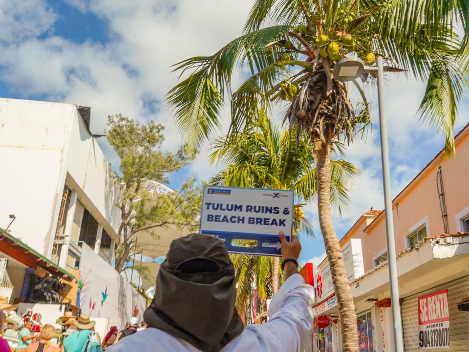 The tour guide leads the group to Tulum with palm trees in the background