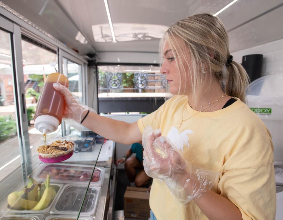 Taylor Brady adds honey to an order at the Bear Fruit Bowls and Coffee food truck on South Tarragona Street in downtown Pensacola on Wednesday, June 28, 2023.