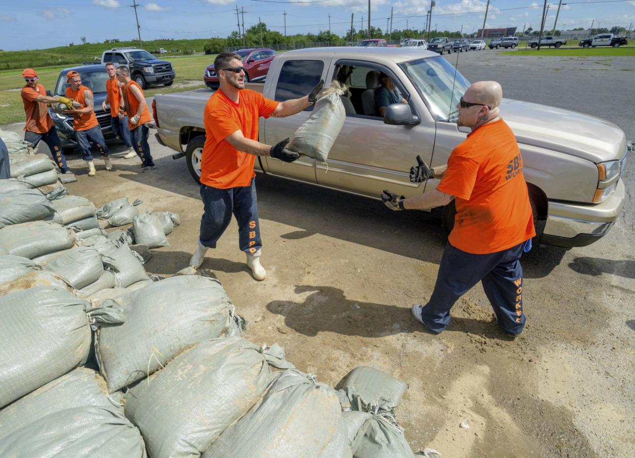 St. Bernard Parish Sheriff's Office inmate workers move free sandbags for residents in Chalmette, La., Thursday, July 11, 2019 ahead of ahead of Tropical Storm Barry from the Gulf of Mexico. (AP Photo/Matthew Hinton)