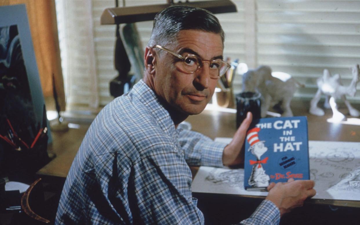 American author and illustrator Dr Seuss sits at his drafting table in his home office with a copy of his book, 'The Cat in the Hat' - Gene Lester /Archive Photos 