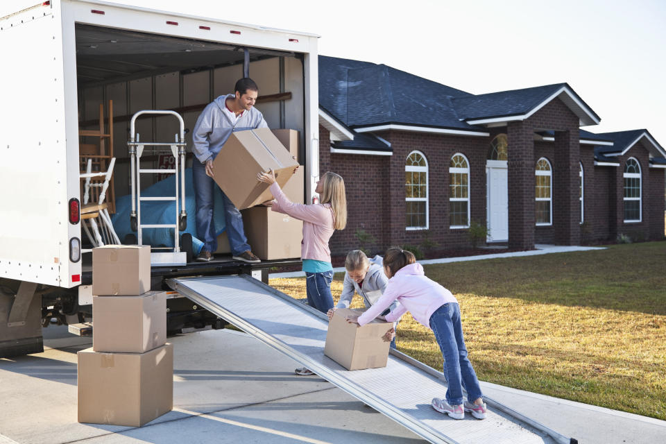 Moving house.  Family loading or unloading moving van.