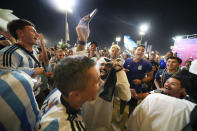 A man wearing traditional Qatari clothing joins a group of supporters from Argentina celebrating outside Lusail Stadium following their team's 2-0 victory over Mexico in a World Cup group C soccer match in Lusail, Qatar, Saturday, Nov. 26, 2022. (AP Photo/Julio Cortez)