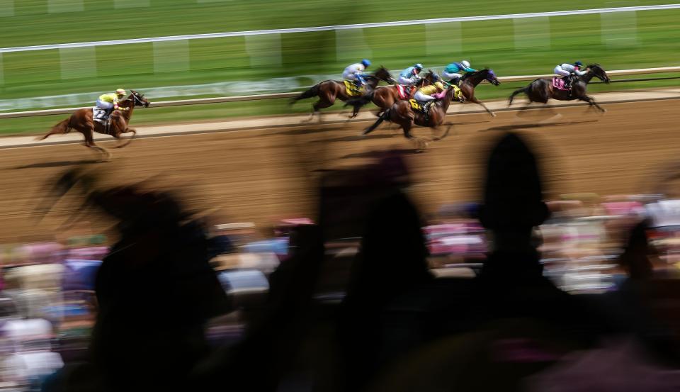 Horses race by the stands as fans cheer Thursday, May 2, 2024, while attending Thurby at Churchill Downs in Louisville, Kentucky.