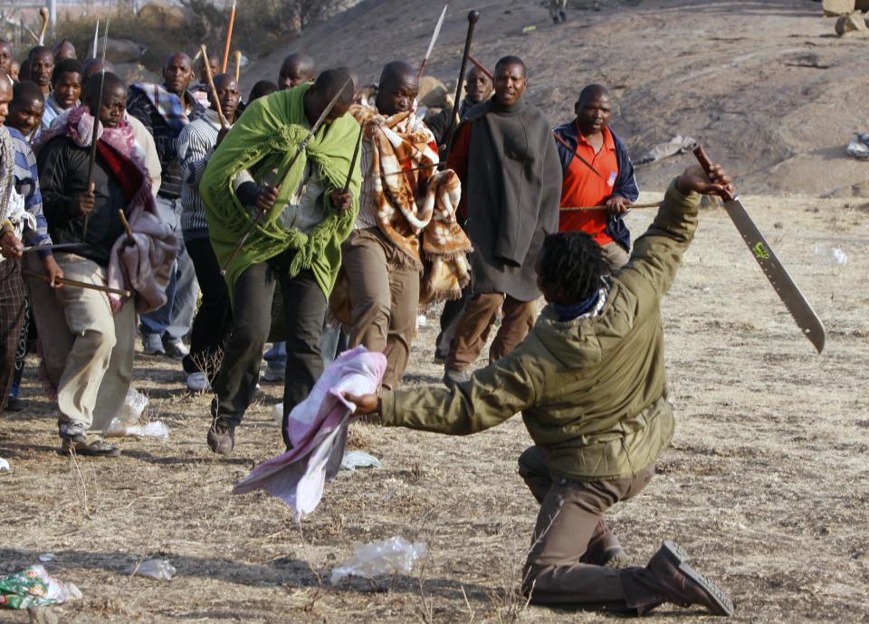 Striking miners sing, chant, march and dance with crudely made weapons and machetes at the Lonmin mine near Rustenburg, South Africa, Wednesday Aug. 15, 2012. Ongoing violence that started last Friday has seen 10 people killed, with no end to the strike in sight. (AP Photo/Denis Farrell)