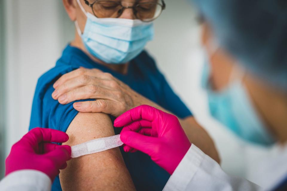 doctor giving first aid bandage after vaccination to senior woman