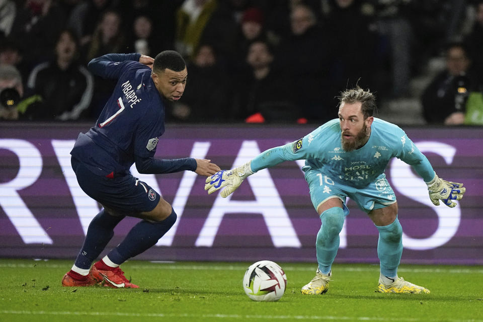 PSG's Kylian Mbappe, left, challenges for the ball with Metz's goalkeeper Alexandre Oukidja during the French League One soccer match between Paris Saint-Germain and Metz at the Parc des Princes in Paris, Wednesday, Dec 20, 2023. (AP Photo/Michel Euler)