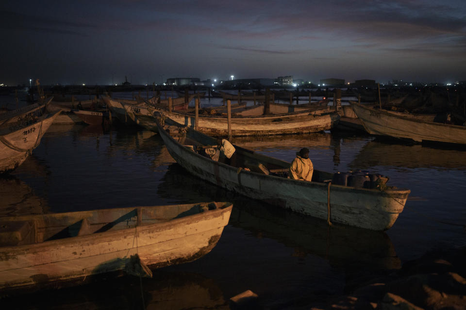 Fishermen aboard a traditional Mauritanian fishing boat, or pirogue, return after a day of work to the port of Nouadhibou, Mauritania, Saturday, Nov. 27, 2021. Every year, hundreds if not thousands of West African migrants disappear trying to reach the Canary Islands and, they believed, better lives in Europe. The real death toll is unknown, and so many people and boats are never seen again. (AP Photo/Felipe Dana)