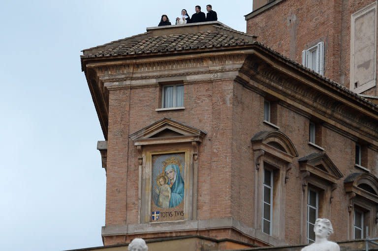 A nun and priests stand at a balcony before pope's first Angelus prayer at St Peter's Square on March 17, 2013