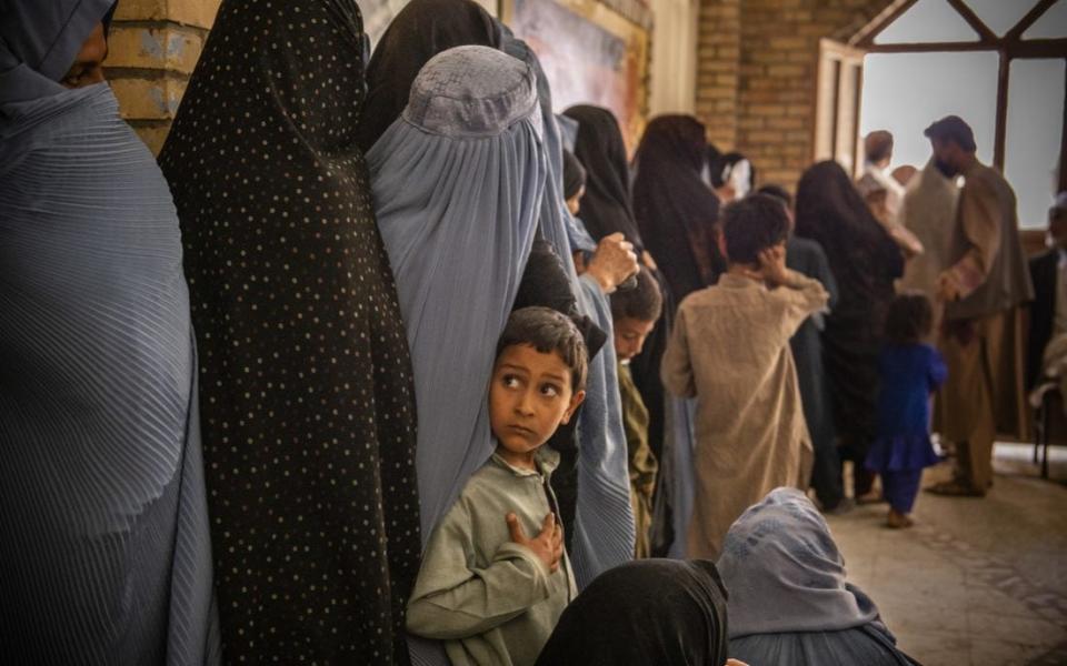 A young boy waits in line with his mother at a food distribution in Afghanistan organised by Oxfam - Kiana Hayeri  /Oxfam