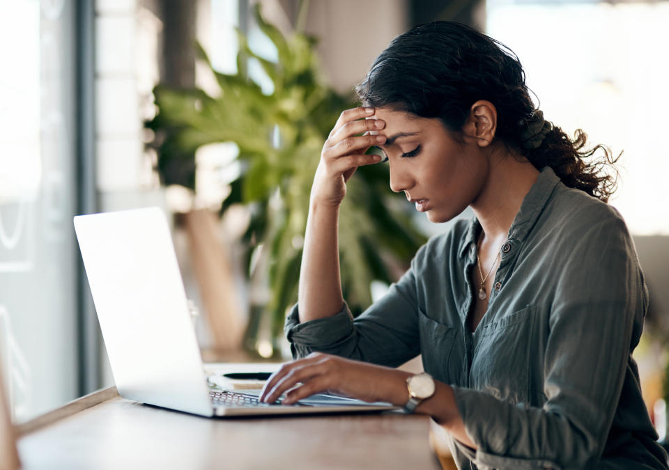 A woman sitting at her laptop looking stressed