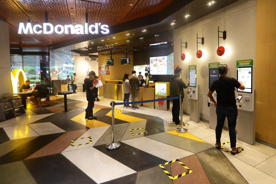 SINGAPORE: People queue to place orders at a McDonald's restaurant with safety distancing markers in place. (Photo by Suhaimi Abdullah/Getty Images)