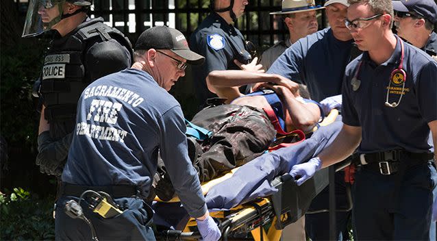 Paramedics rush a stabbing victim away on a gurney. Photo: AP