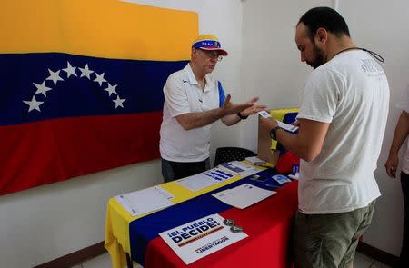 A Venezuelan man living in Nicaragua explains how to cast a vote during an unofficial plebiscite against Venezuela's President Nicolas Maduro's government in Managua, Nicaragua July 16,2017.REUTERS/Oswaldo Rivas