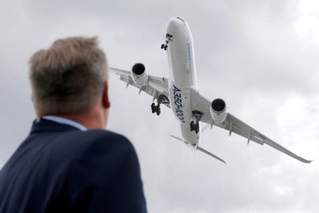 A visitor looks at an Airbus A350-1000 as he performs during the 53rd International Paris Air Show at Le Bourget Airport near Paris