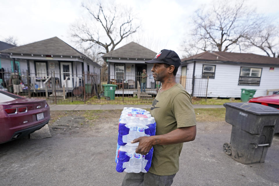 Ernest Collins carries cases of water back to his home, which was without running water for days after a recent winter storm, Friday, Feb. 26, 2021, in Houston. Local officials, including Houston Mayor Sylvester Turner, say they have focused their efforts during the different disasters on helping the underserved and under-resourced but that their work is far from complete. (AP Photo/David J. Phillip)