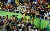 The Jamaican national climbs over photographers to greet fans in the crowd. Photo: Getty