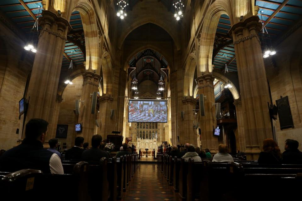 People gather in St. Andrew's Cathedral in Sydney, Australia, to watch the Queen's funeral on September 19, 2022.