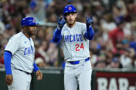 Chicago Cubs' Cody Bellinger, right, celebrates his run-scoring triple against the Arizona Diamondbacks as Cubs third base coach Willie Harris looks on during the fifth inning of a baseball game Tuesday, April 16, 2024, in Phoenix. (AP Photo/Ross D. Franklin)