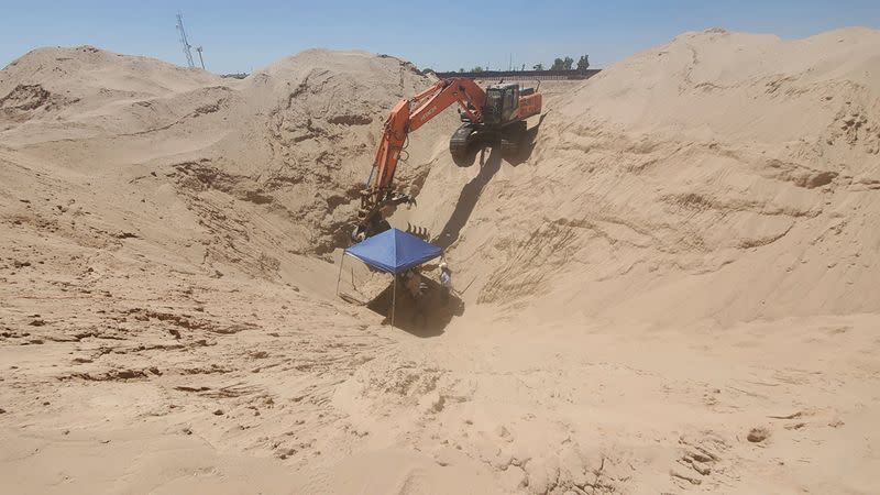 An excavator digs at the entrance to an unfinished cross-border tunnel in the sandy Sonoran desert terrain outside of Yuma