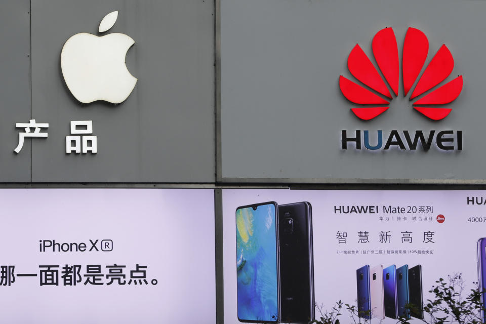 FILE - In this Thursday, March 7, 2019, file photo, logos of Apple and Huawei are displayed outside a mobile phone retail shop in Shenzhen, China's Guangdong province. Few U.S. companies are more vulnerable to a trade war with China than Apple. The Trump administration’s decision to bar U.S. technology sales to Huawei, one of China’s leading brands, might put Apple in the crosshairs. (AP Photo/Kin Cheung, File)