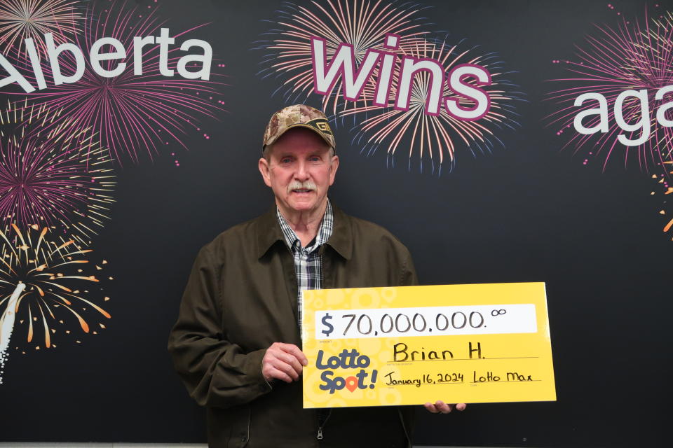 Man holding a $70 million Lotto Max winning cheque.