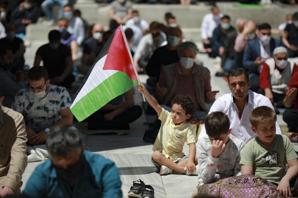 A child holds a Palestinian flag during Friday prayers outside Fatih mosque in Istanbul, Friday, May 4, 202. People in Turkey have been demonstrating this week against Israel and in support of Palestinians, killed in the recent escalation of violence in Jerusalem and the Gaza Strip, without much interference from the police despite a strict lockdown to curb COVID-19 infections that have ordered people to stay home until May 17.(AP Photo/Emrah Gurel)