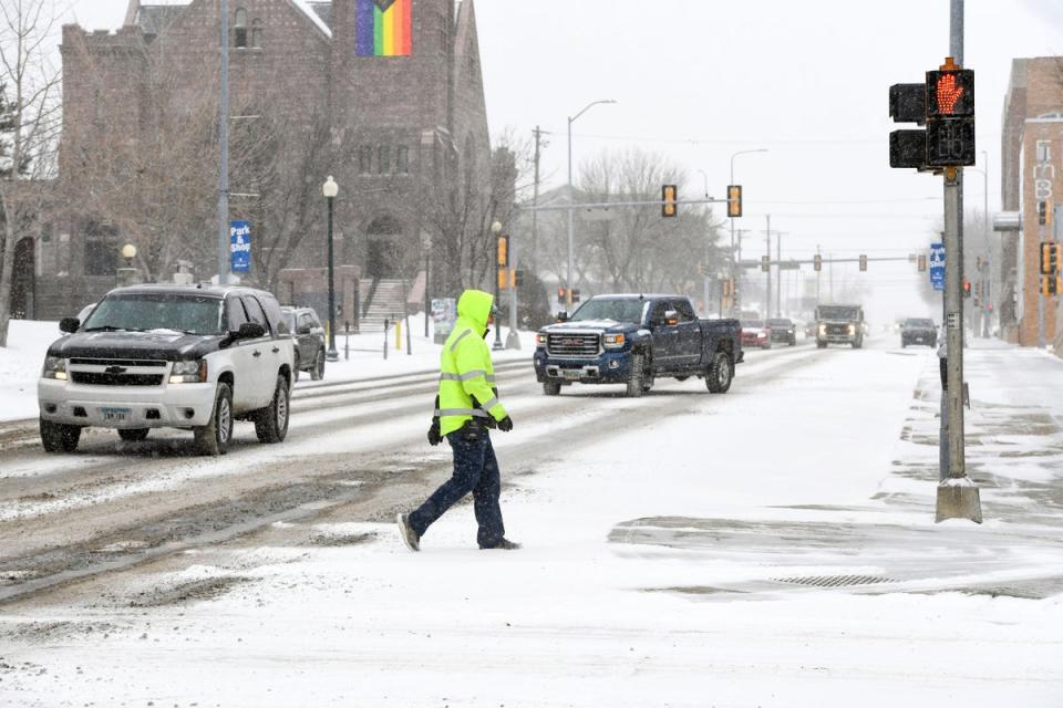 A pedestrian walks across town as the first snow falls ahead of a winter storm on Tuesday in Sioux Falls, South Dakota (AP)