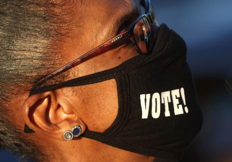 An attendee wears a protective face covering that reads ‘vote’ during a “Get Out the Early Vote” drive-in campaign event with Democratic U.S. Senate candidates Jon Ossoff and Rev. Raphael Warnock on October 29, 2020 in Columbus, Georgia. With less than a week to go until Election Day, Democratic candidates for the U.S. Senate in Georgia are continuing to campaign throughout the state. (Photo by Justin Sullivan/Getty Images)