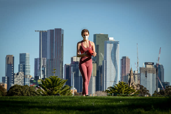 A woman plays football in the afternoon sun at Princes Park in Carlton.