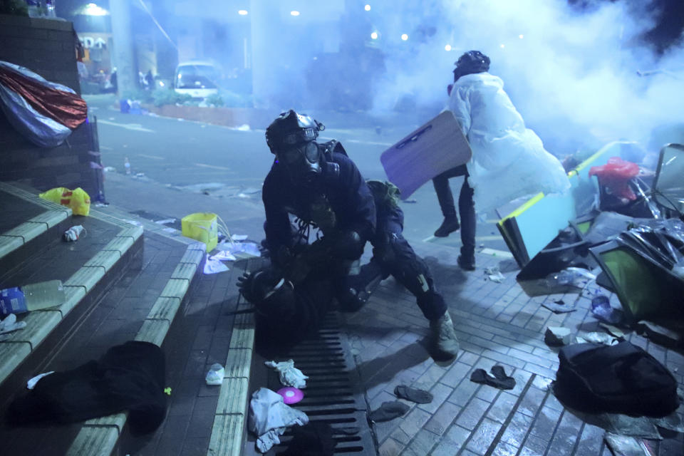 A policeman in riot gear detains a protester outside of Hong Kong Polytechnic University as police storm the campus in Hong Kong, early Monday, Nov. 18, 2019. Fiery explosions were seen early Monday as Hong Kong police stormed into a university held by protesters after an all-night standoff. (AP Photo/Kin Cheung)