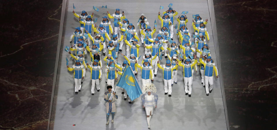 Yerdos Akhmadiyev of Kazakhstan holds the national flag and enters the arena with his teammates during the opening ceremony of the 2014 Winter Olympics in Sochi, Russia, Friday, Feb. 7, 2014. (AP Photo/Charlie Riedel)