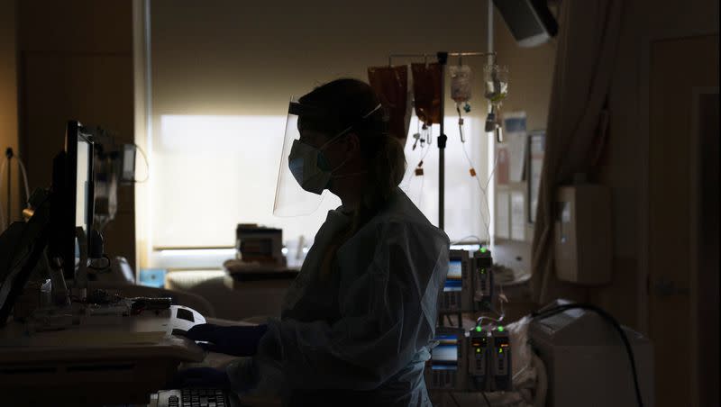 A registered nurse works on a computer while assisting a COVID-19 patient in Los Angeles. Three counties in California’s Bay Area have imposed new mask mandates for health care personnel.