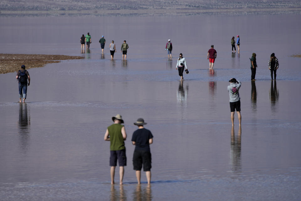 People wade through water at Badwater Basin, Thursday, Feb. 22, 2024, in Death Valley National Park, Calif. The basin, normally a salt flat, has filled from rain over the past few months. (AP Photo/John Locher)