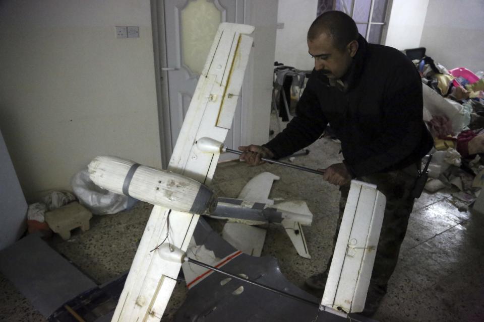 In this Friday, Jan. 27, 2017 photo, an Iraqi officer inspects drones belonging to Islamic State militants in Mosul, Iraq. Islamic State is hacking store-bought drone technology, using rigorous testing and tactics that mimic those used by U.S. unmanned aircraft to adapt to diminishing numbers of fighters and a battlefield that is increasingly difficult to navigate on the ground. (AP Photo/ Khalid Mohammed)