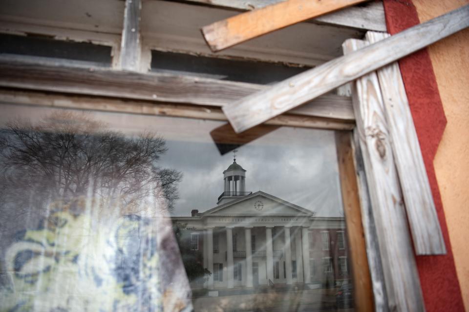 The Noxubee County Courthouse is reflected in an abandoned shop in Macon on Feb. 8, 2023.