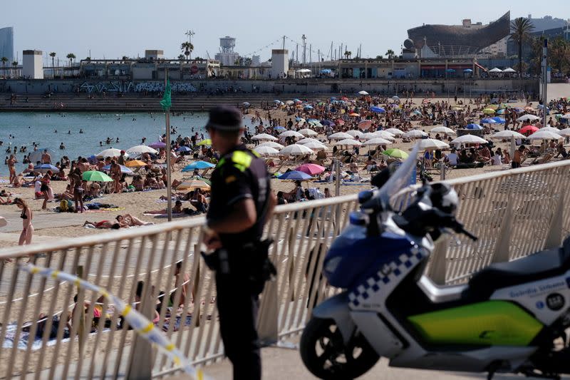 FILE PHOTO: A police officer looks on as people enjoy the sunny weather on the beach, as Spain officially reopens the borders amid the coronavirus disease (COVID-19) outbreak, in Barcelona