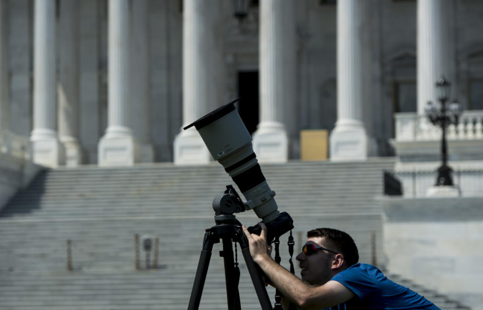 A news photographer adjusts his telephoto lens equipped with a filter in front of the U.S. Capitol on Monday, Aug. 21, 2017, in preparation for today's solar eclipse.&nbsp;