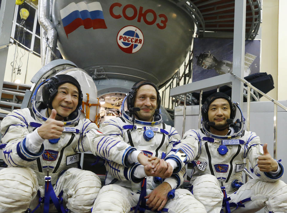 Roscosmos cosmonaut Alexander Misurkin, center, and space flight participants Yusaku Maezawa, left, and Yozo Hirano pose for a picture during a training session ahead of the expedition to the International Space Station at the Gagarin Cosmonauts' Training Center in Star City outside Moscow, Russia, Thursday, Oct. 14, 2021. A Japanese fashion tycoon who's booked a SpaceX ride to the moon is going to try out the International Space Station first. Yusaku Maezawa announced that he's bought two seats on a Russian Soyuz capsule. He'll blast off in December on the 12-day mission with his production assistant and a professional cosmonaut. (Shamil Zhumatov/Pool Photo via AP)