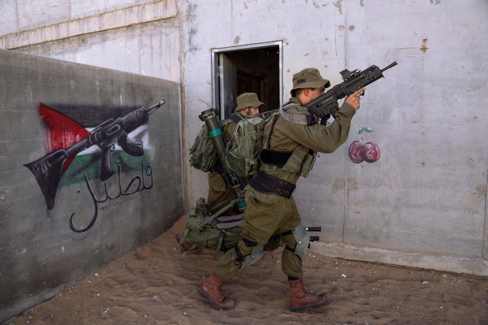 Israeli soldier carry ammunition next to a graffiti featuring the Palestinian flag, during an urban warfare exercise at an army training facility at the Zeelim army base, southern Israel, May 25, 2022.