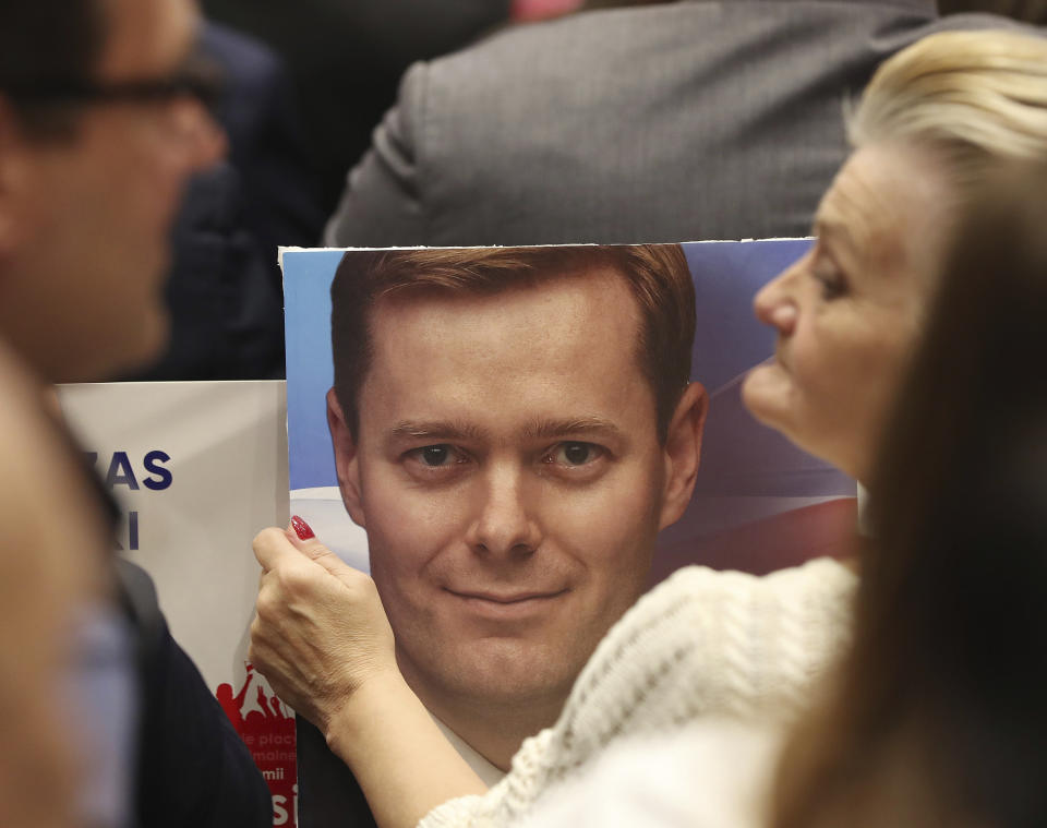 In this photo taken Tuesday Oct. 8, 2019 a supporter of Poland's ruling right-wing party is holding a photo of one of the Law and Justice party's candidates at a convention in Warsaw, Poland ahead of Sunday parliamentary election in which the Law and Justice party is hoping to win a second term in power. (AP Photo/Czarek Sokolowski)