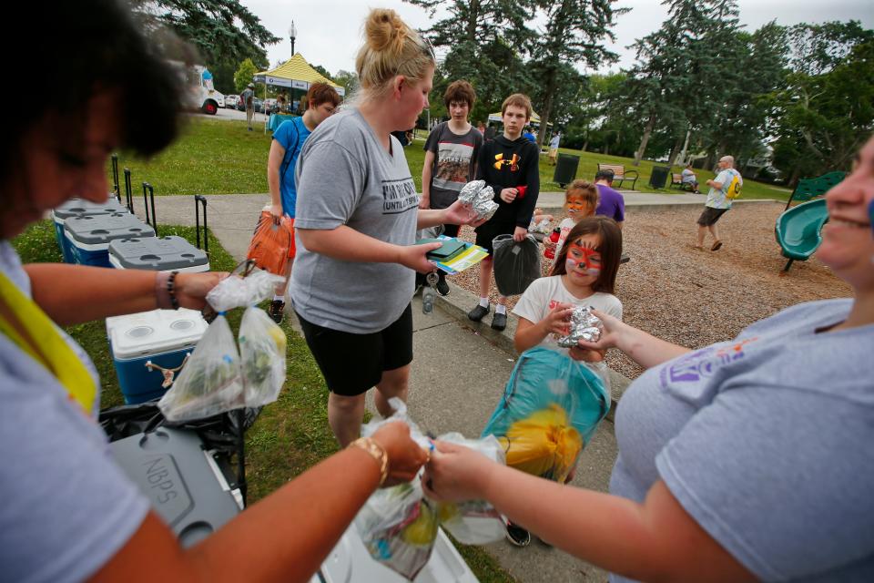 Joyce Hurson, left, and Bethannie Adair, right, of Play in the Park hand out meals to kids as part of the Summer Eats program kicks which started today at Hazelwood Park in New Bedford.