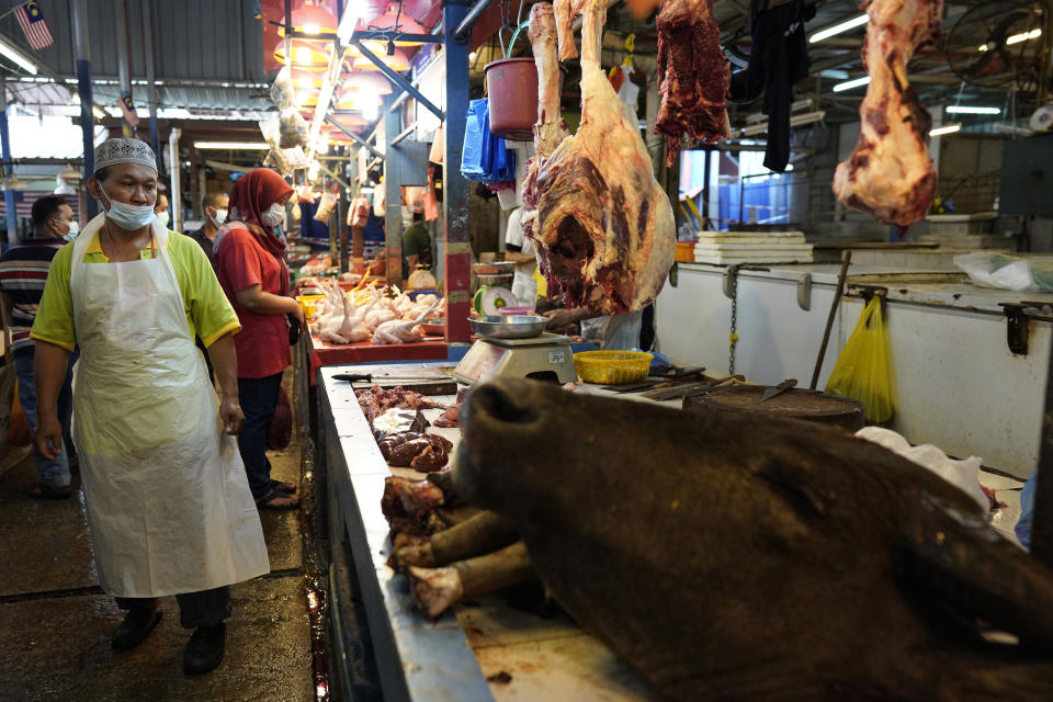 A poultry butcher wearing a face mask to help curb the spread of the coronavirus waits for customers at a wet market in downtown Kuala Lumpur, Malaysia, Friday, April 24, 2020. Malaysia, along with neighboring Singapore and Brunei, has banned popular Ramadan bazaars where food, drinks and clothing are sold in congested open-air markets or road-side stalls. The bazaars are a source of key income for many small traders, some who have shifted their businesses online. (AP Photo/Vincent Thian)