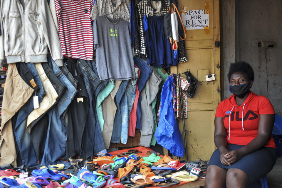 In this photo taken Saturday, June 20, 2020, Grace Twisimire, 25, sits in her once-thriving shop selling clothes and plastic shoes in the capital Kampala, Uganda. The COVID-19 pandemic means that millions of women in Africa and other developing regions could lose years of success in contributing to household incomes, asserting their independence and expanding financial inclusion. (AP Photo/Ronald Kabuubi)