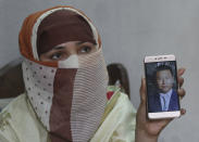 In this May 22, 2019 photo, Sumaira a Pakistani woman, shows a picture of her Chinese husband in Gujranwala, Pakistan. Sumaira, who didn't want her full name used, was raped repeatedly by Chinese men at a house in Islamabad where she was brought to stay after her brothers arranged her marriage to an older Chinese man. Her father had died when she was young, her mother was poor and her brothers were offered money to marry her to a Chinese businessman. (AP Photo/K.M. Chaudary)