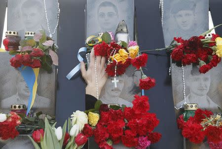 A demonstrator places flowers at the monument of the so-called "Nebesna Sotnya" (Heavenly Hundred), the anti-government protesters killed during the Ukrainian pro-European Union (EU) mass protests in 2014, during a rally commemorating the third anniversary of protests, in central Kiev, Ukraine February 20, 2017. REUTERS/Valentyn Ogirenko